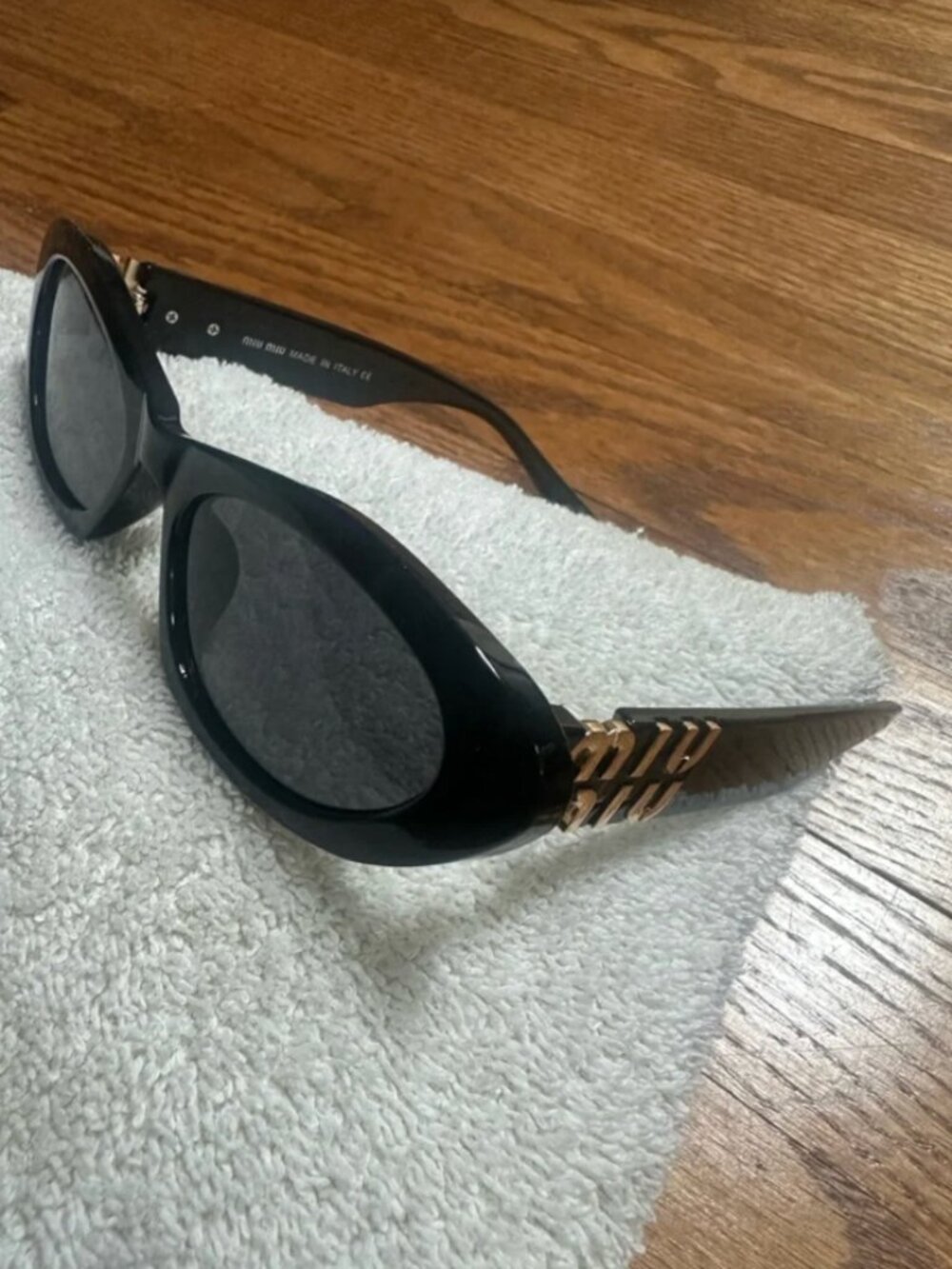 Miu Miu Black Oval Sunglasses with Gold Logo Accents
